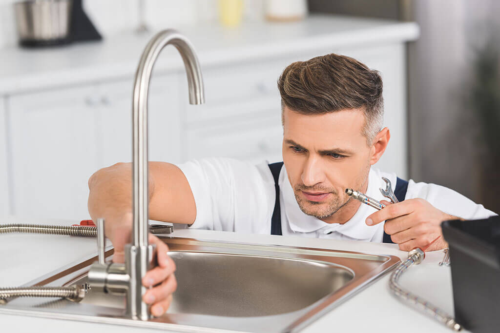 Plumber inspecting a kitchen faucet and sink